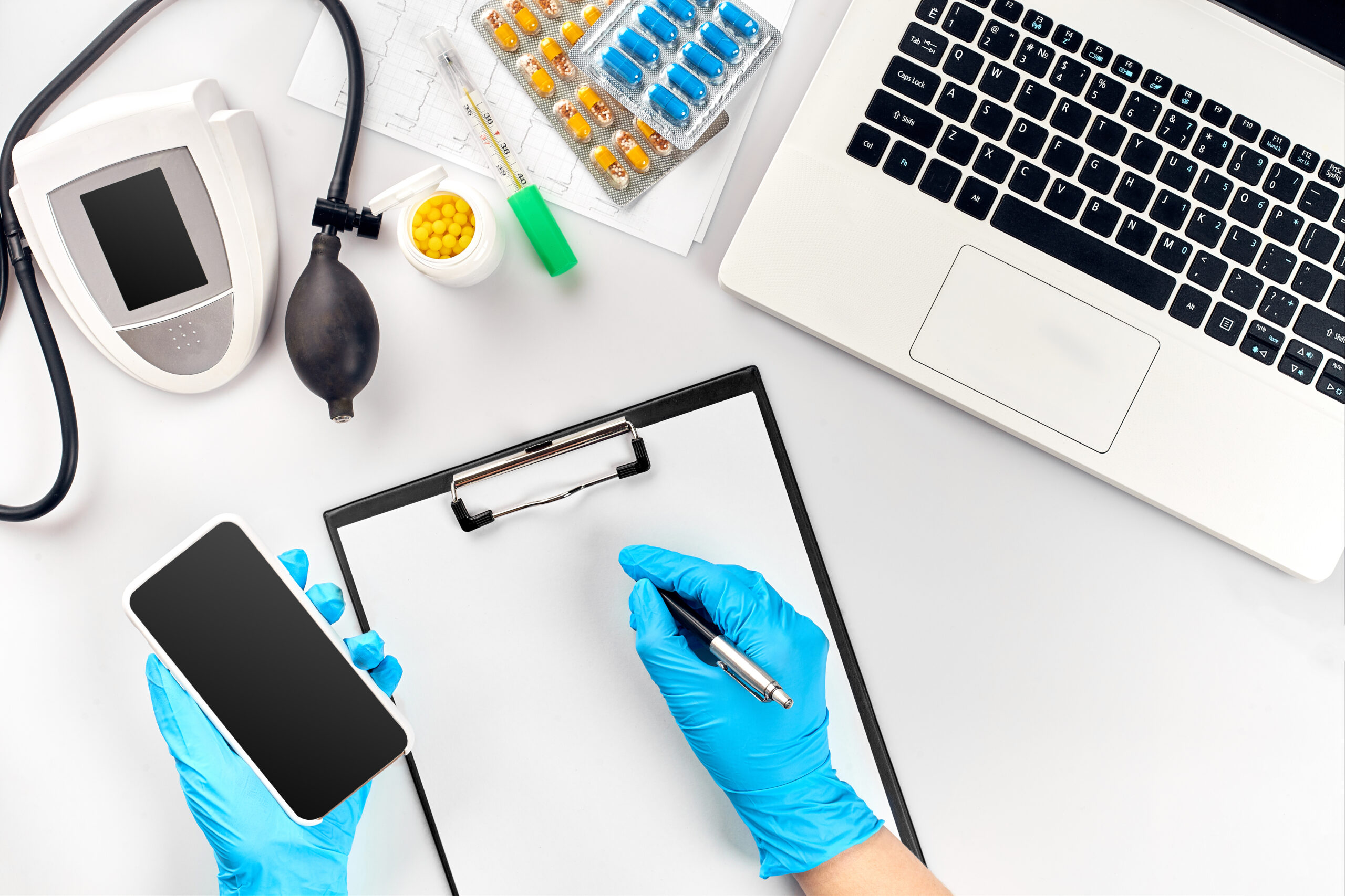 Doctor s table, tools, medical instruments, therapist tonometer, blood pressure, work in hospital on white background flat lay. The doctor's hand in a blue glove records the indicators on a white paper blank. Top view. Still life. Copy space