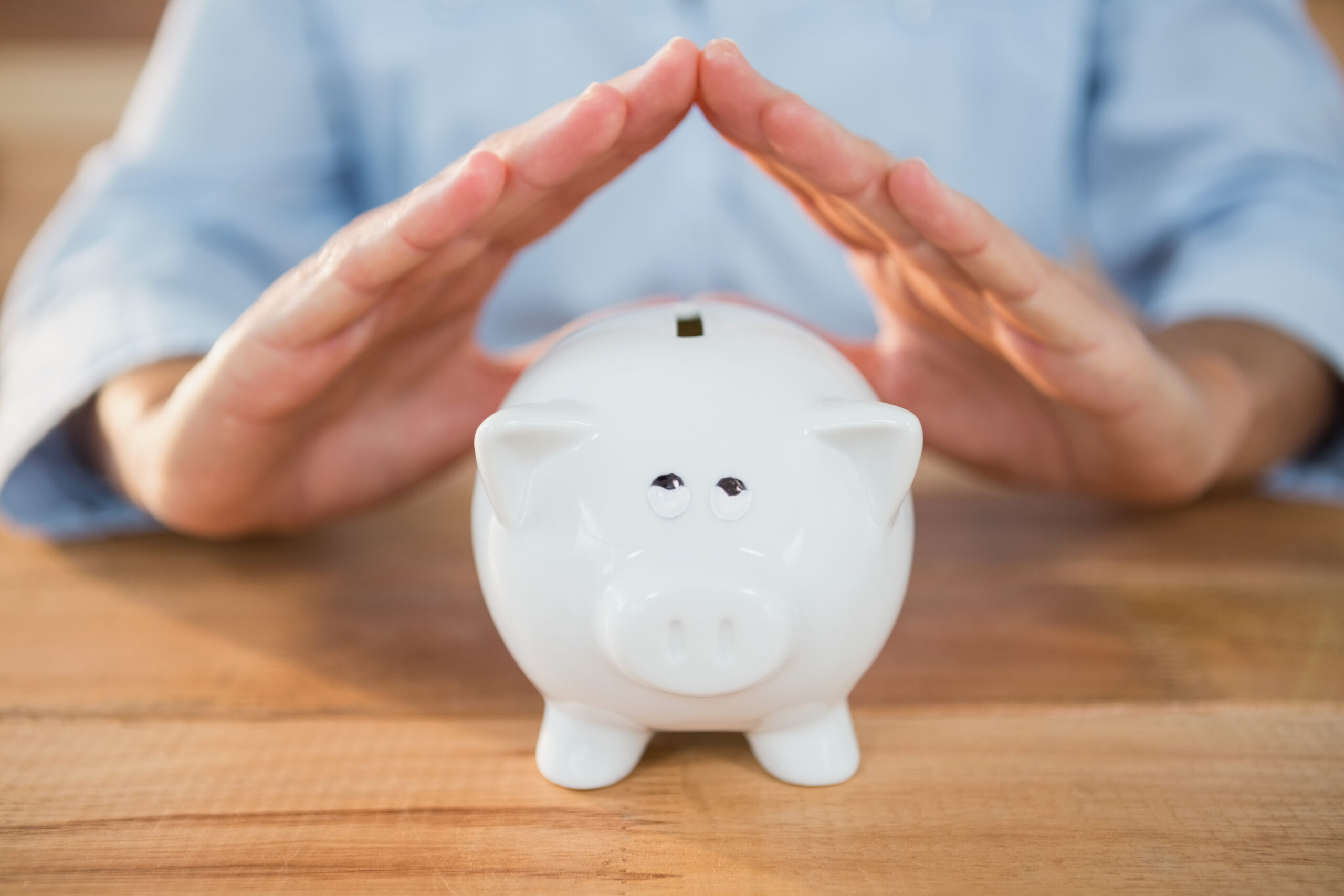 Mid section of man making a roof gesture on piggy bank